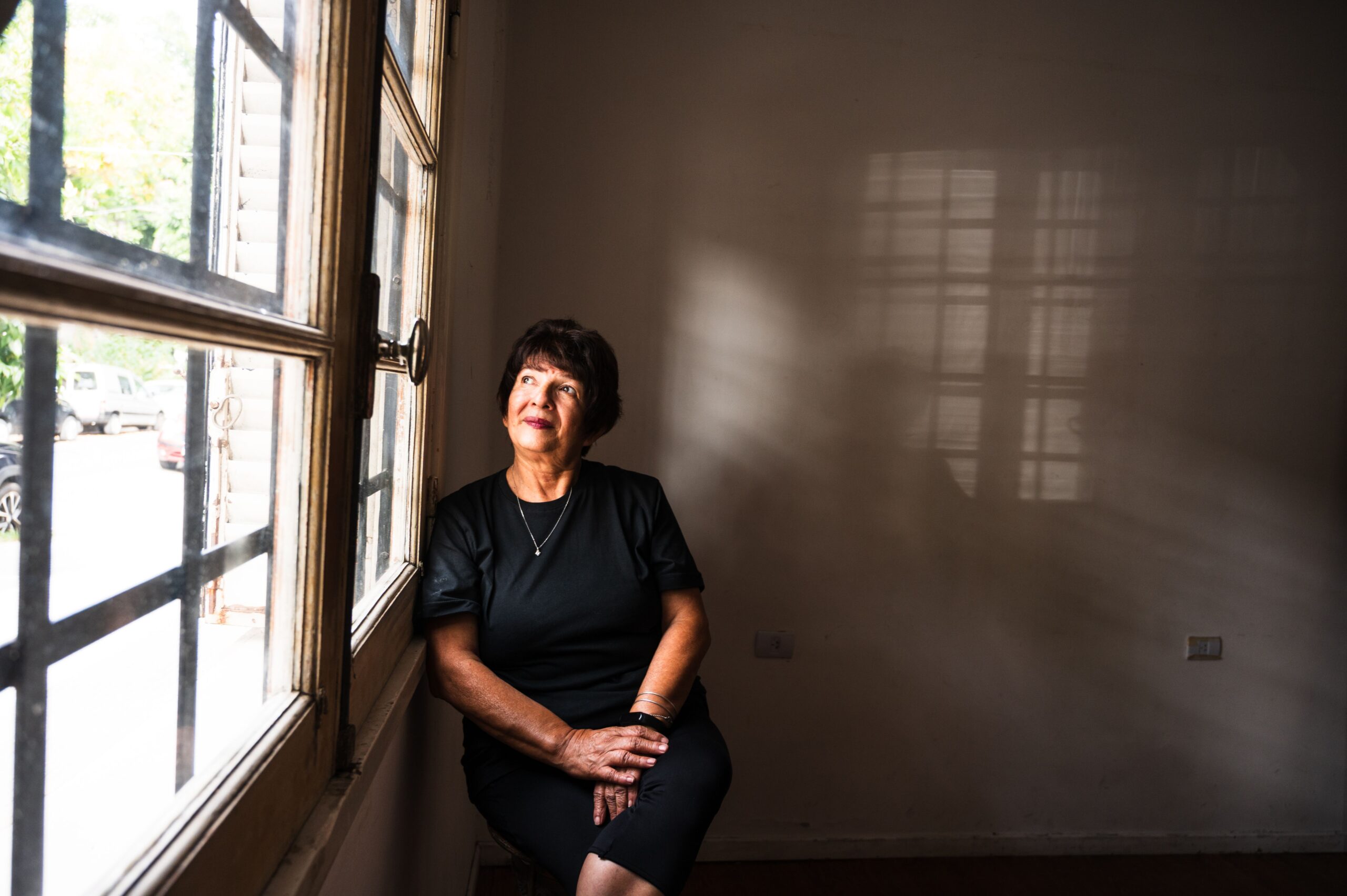A Surviving Spouse sitting by a window in a softly lit room